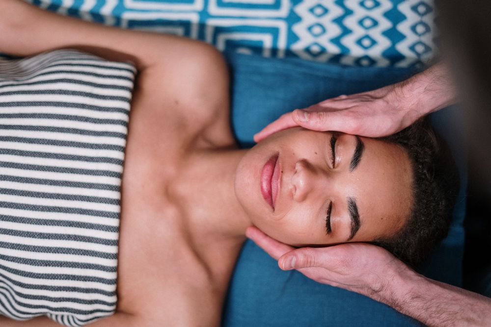 Therapist massaging the head and temples of a relaxed guest