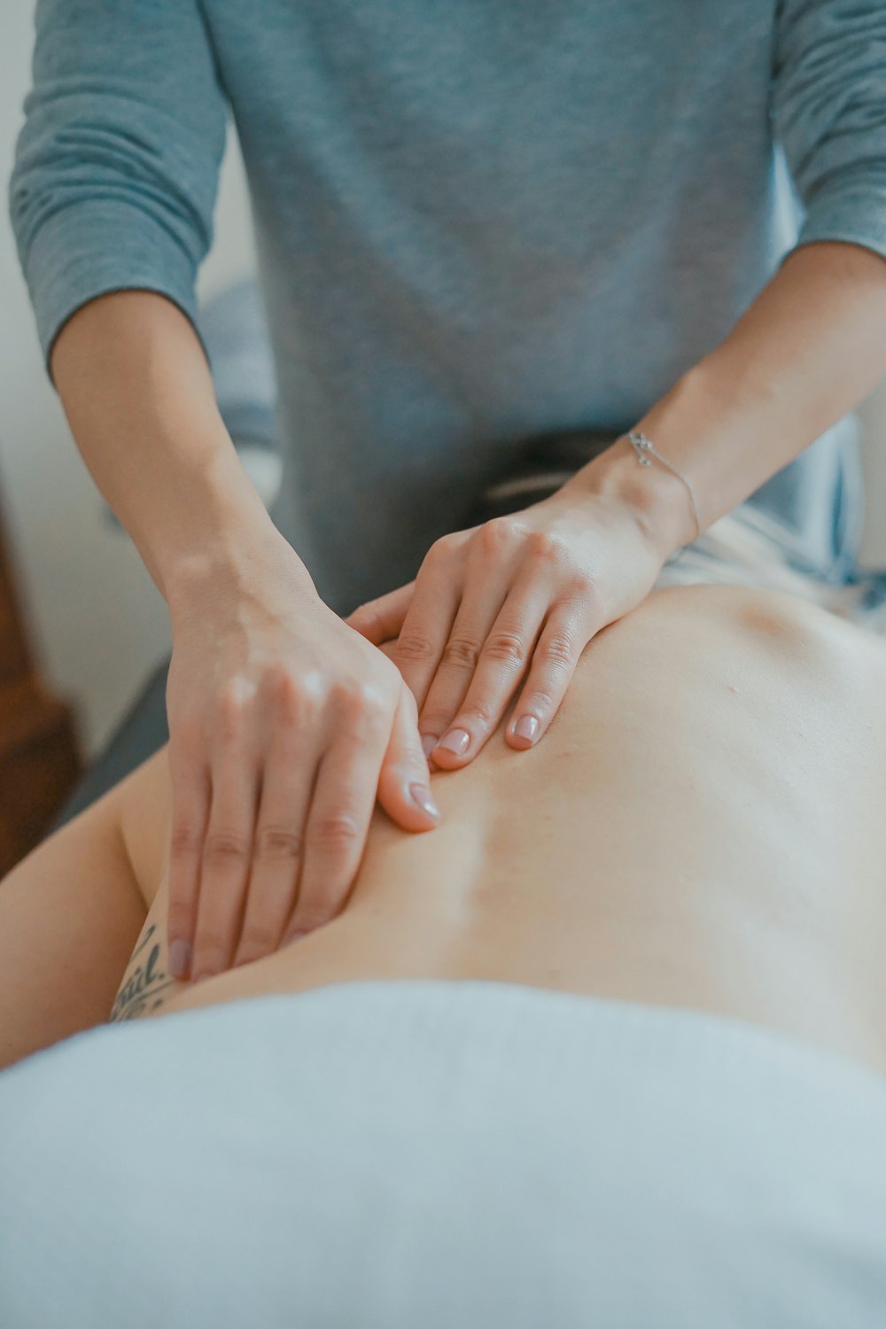 Therapist hands performing long flowing strokes along the back