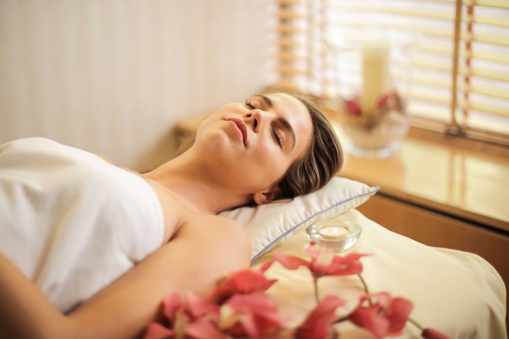 Woman resting peacefully on the treatment table among flower petals
